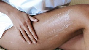 woman putting moisturiser on after leg waxing